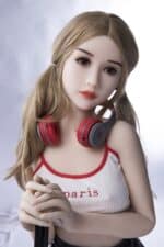 Realistic sex doll with headphones and blonde hair, dressed in a Paris-themed tank top, posing in a studio setting.
